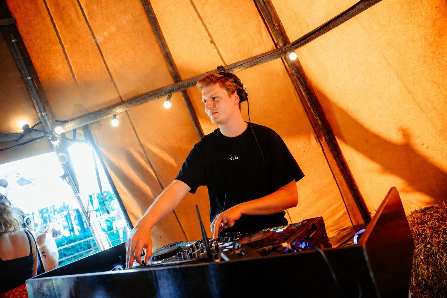 DJ Surleau behind the decks in a warm festival tent