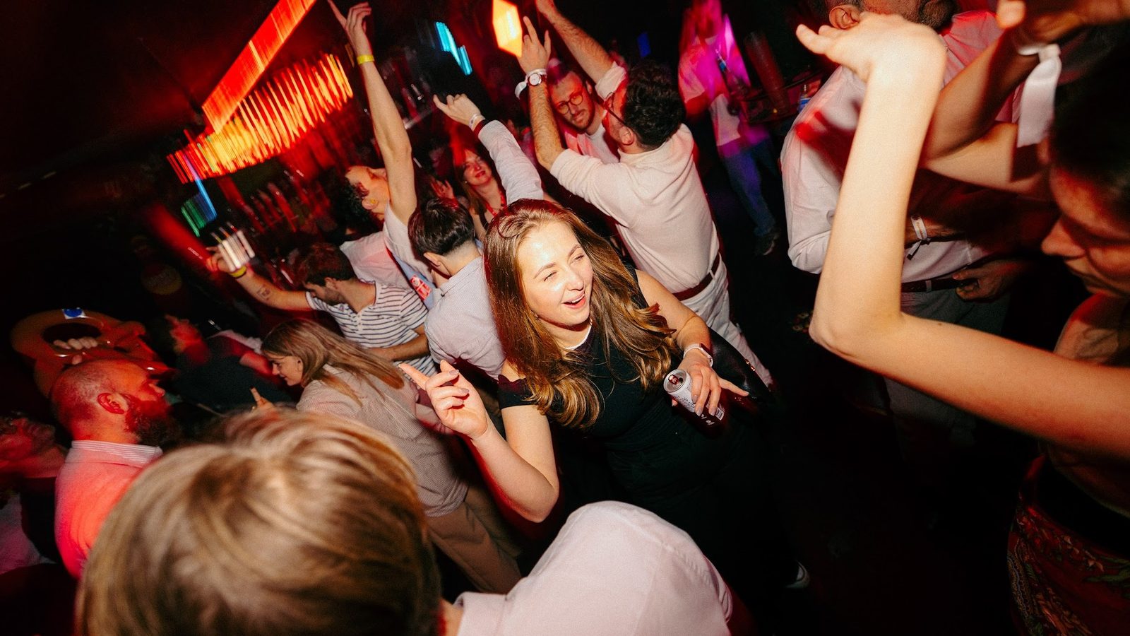 Night-time party setting with dancing crowd and colourful lights